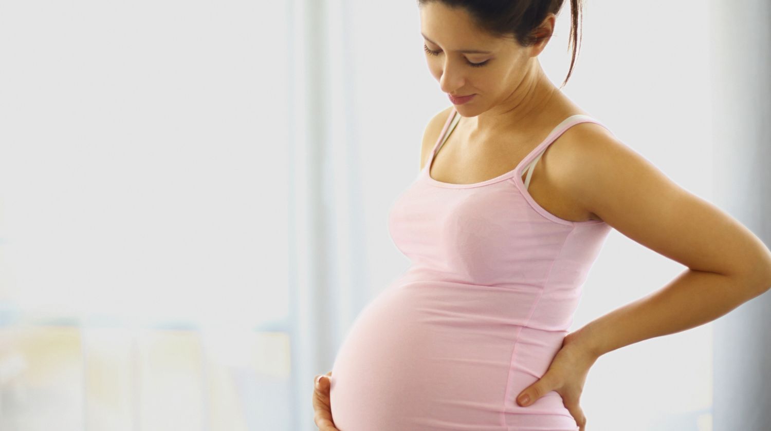 Trudna žena drži se za stomak gleda dole