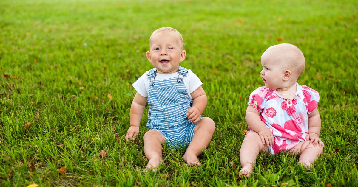 beba dečak i bebaq devojčica sede na travi