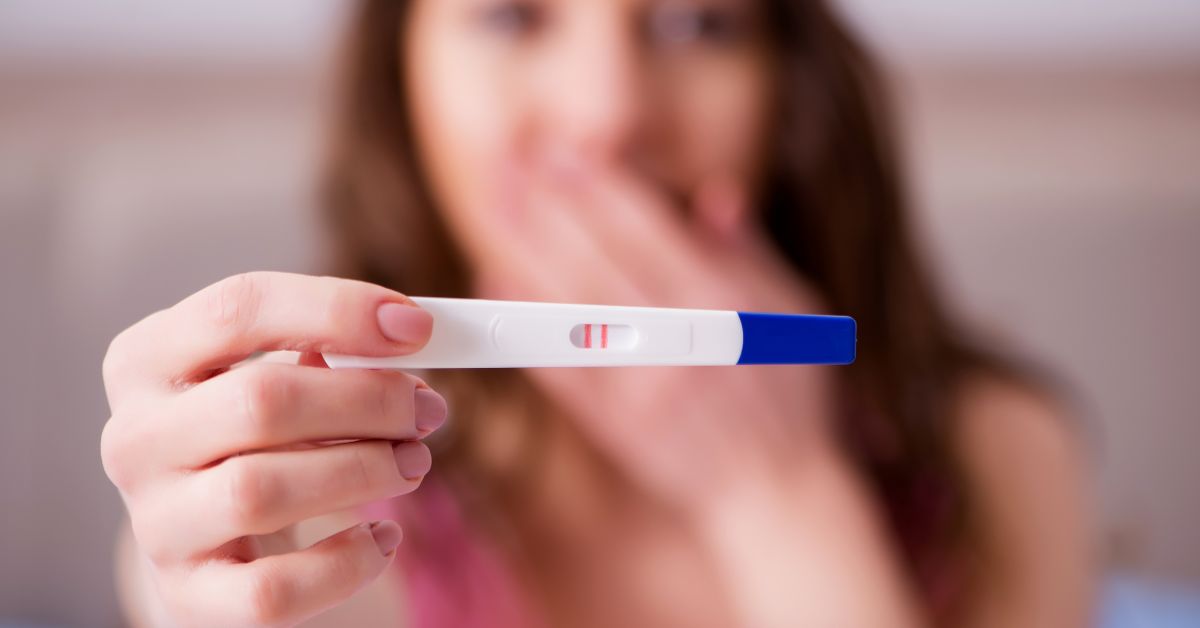 Žena pokazuje pozitivan test na trudnoću