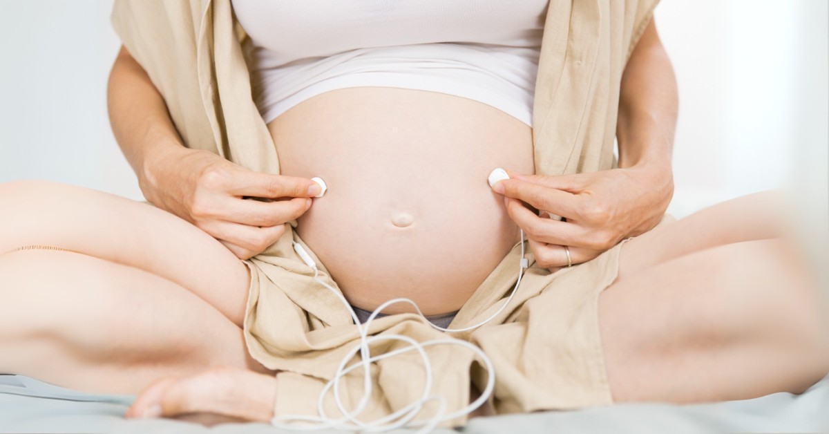 trudnica drži slušalice na stomaku