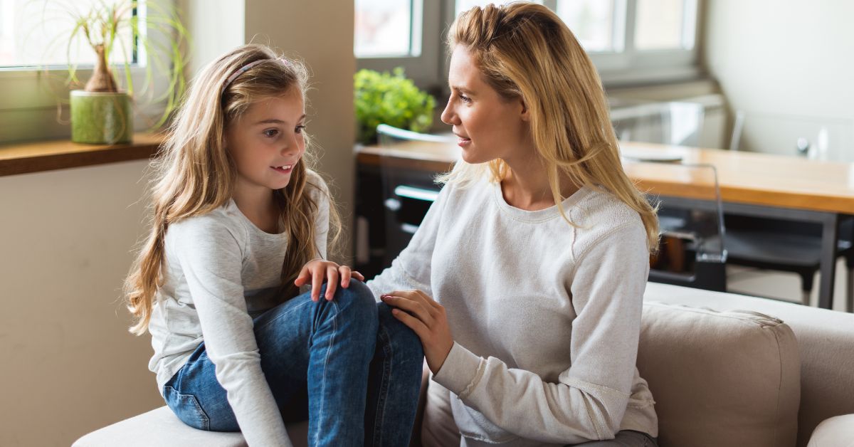 Mama i ćerka sede na kauču razgovaraju