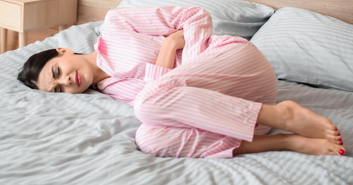 Bol u stomaku žena leži na krevetu