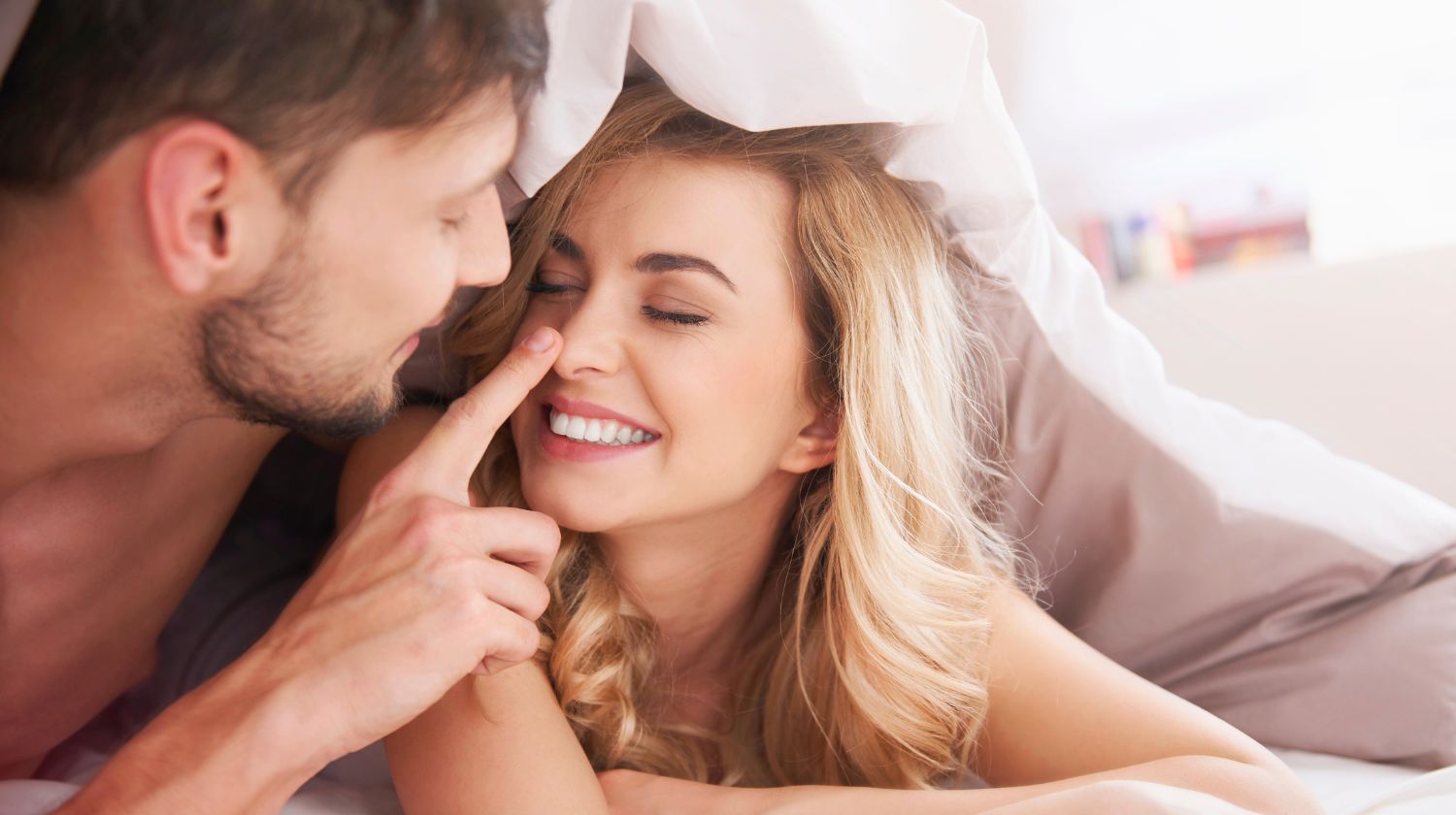 Muškarac i žena u krevetu razmenjuju nežnosti