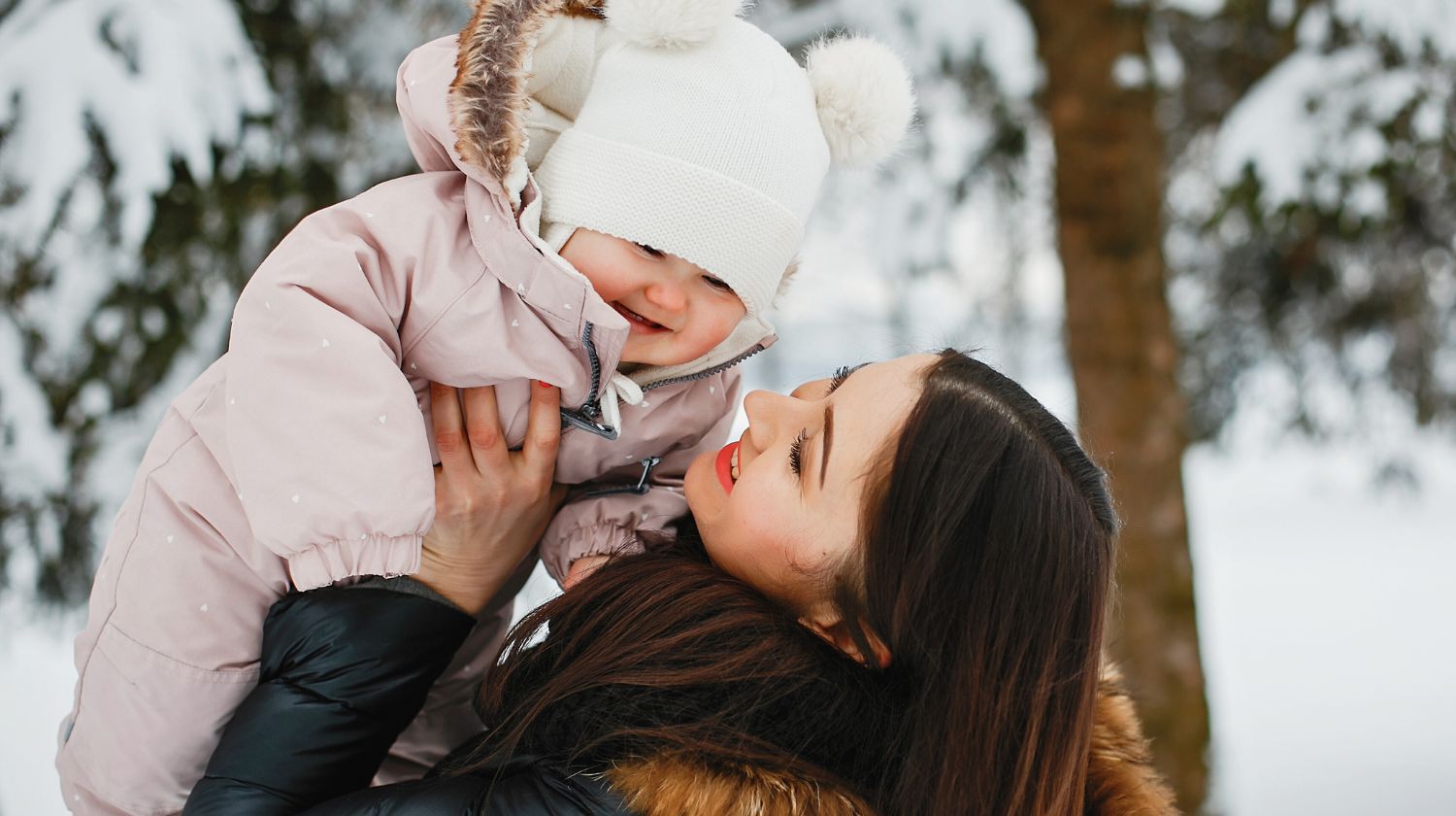 Mama drži bebu u zimskom odelu
