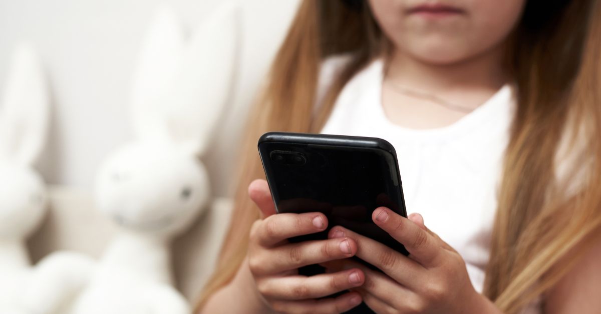 Devojčica drži mobilni telefon u ruci