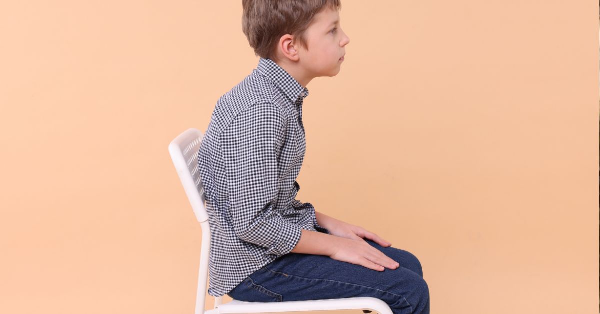 Dečak sedi na stolici kriva kičma