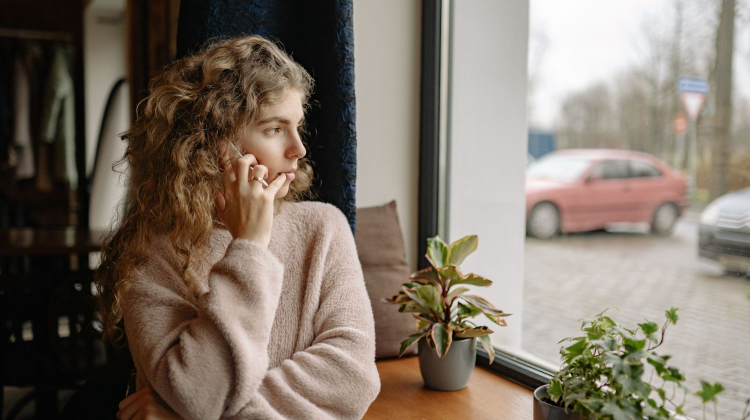 Zena gleda kroz prozor zabrinuto