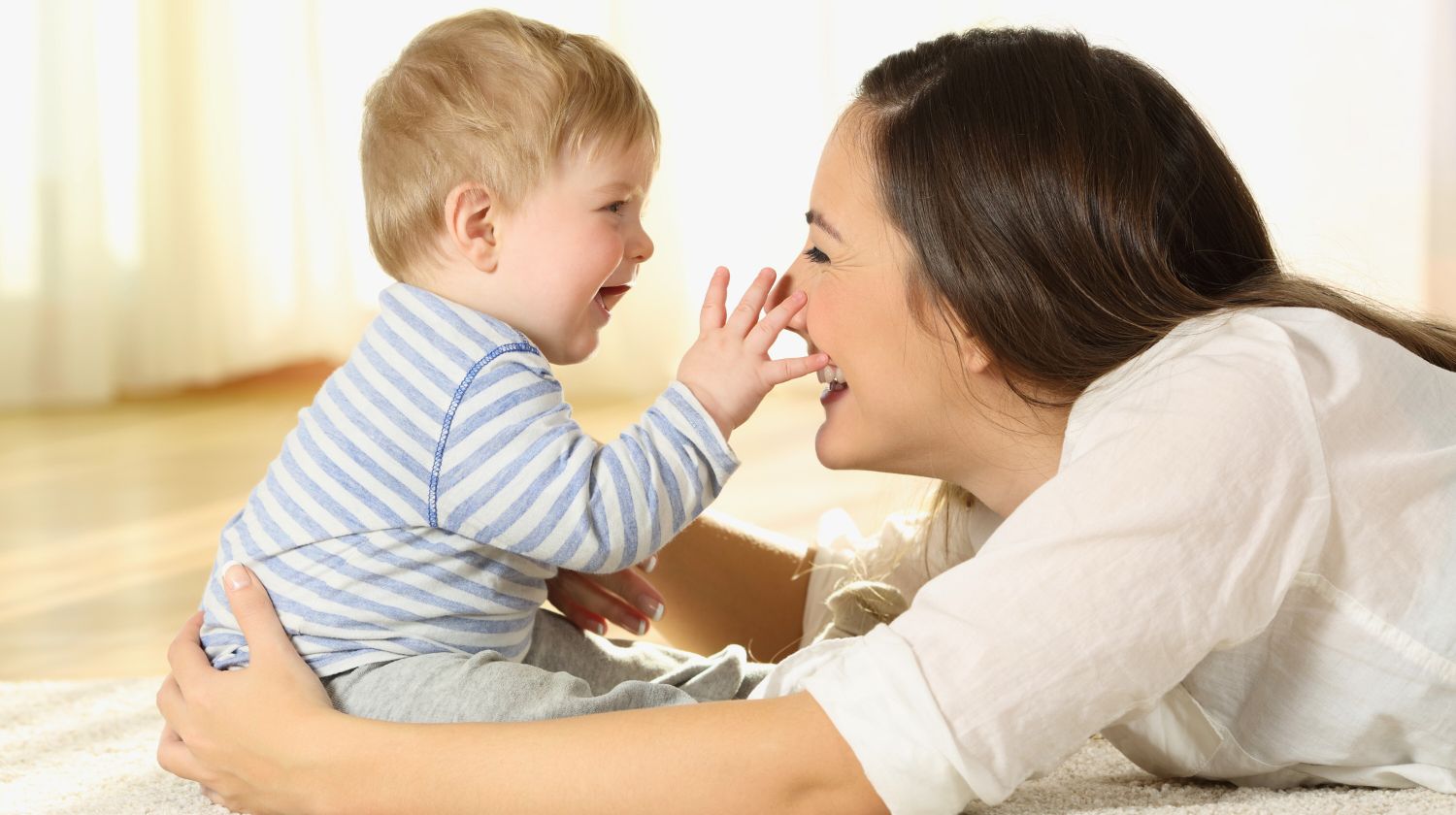 Beba sedi na podu sa mamom smeju se