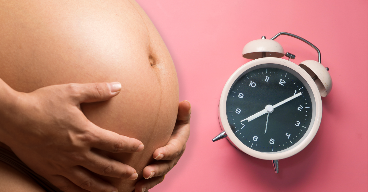 trudnica drži stomak, pored je sat