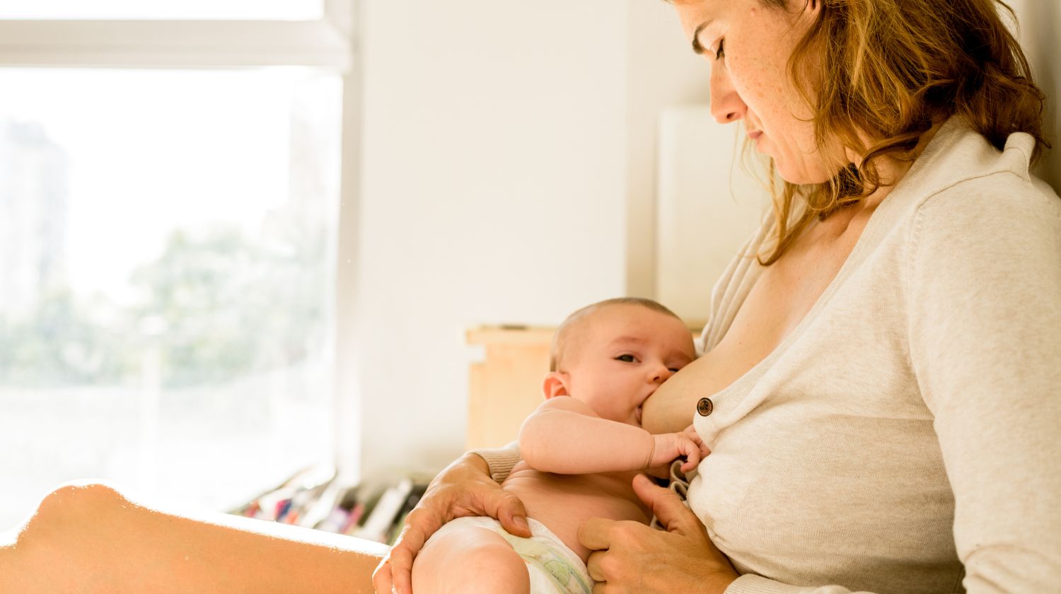 Mama doji bebu pored prozora u kući