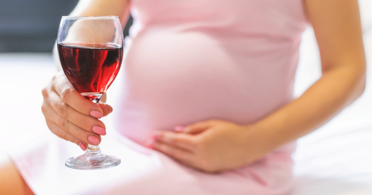 Trudna žena drži čašu vina u ruci