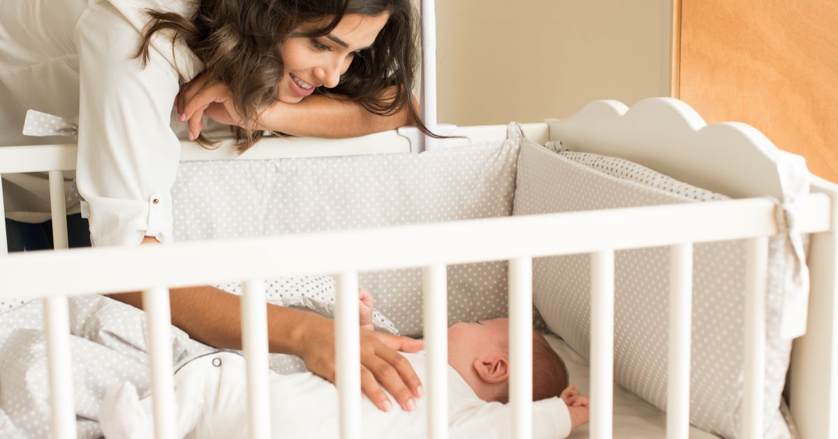 Mama uspavljuje bebu u krevecu