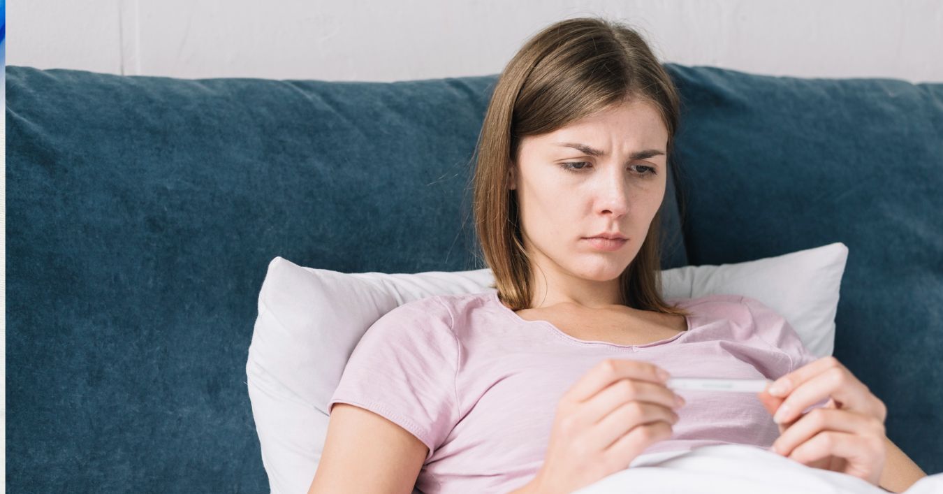 mlada žena u krevetu gleda u toplomer