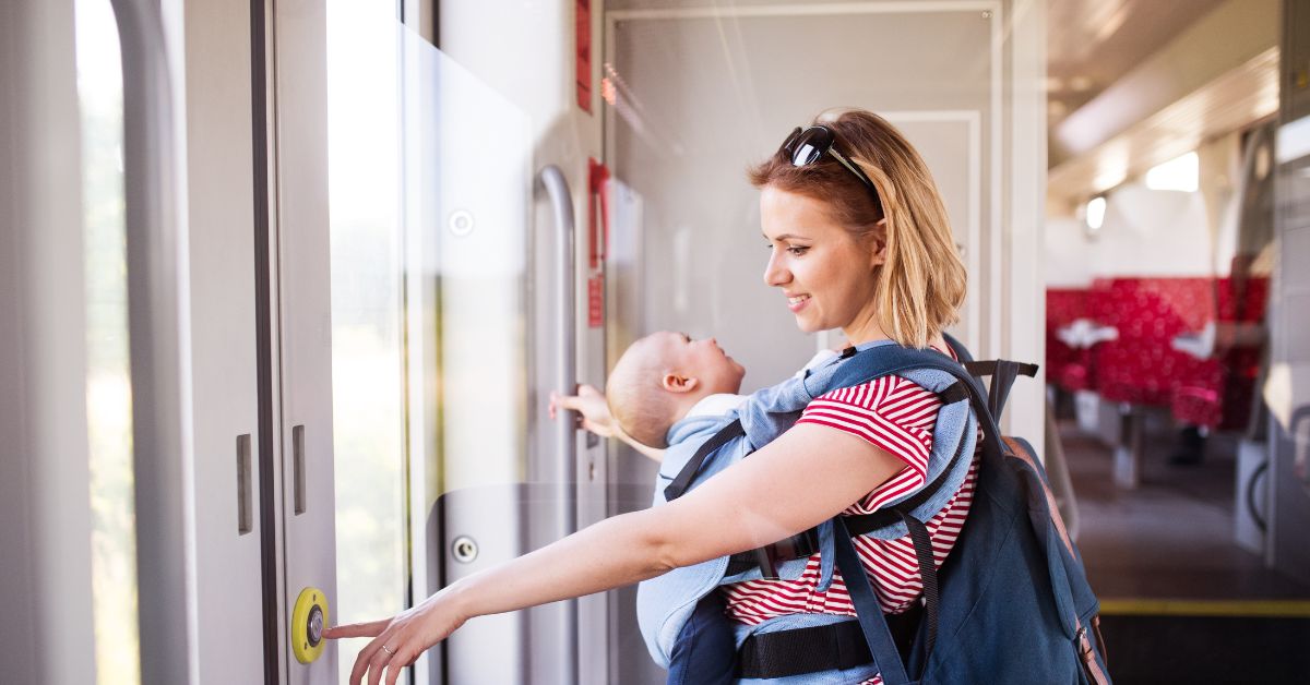 majka nosi bebu u nosiljci na aerodromu