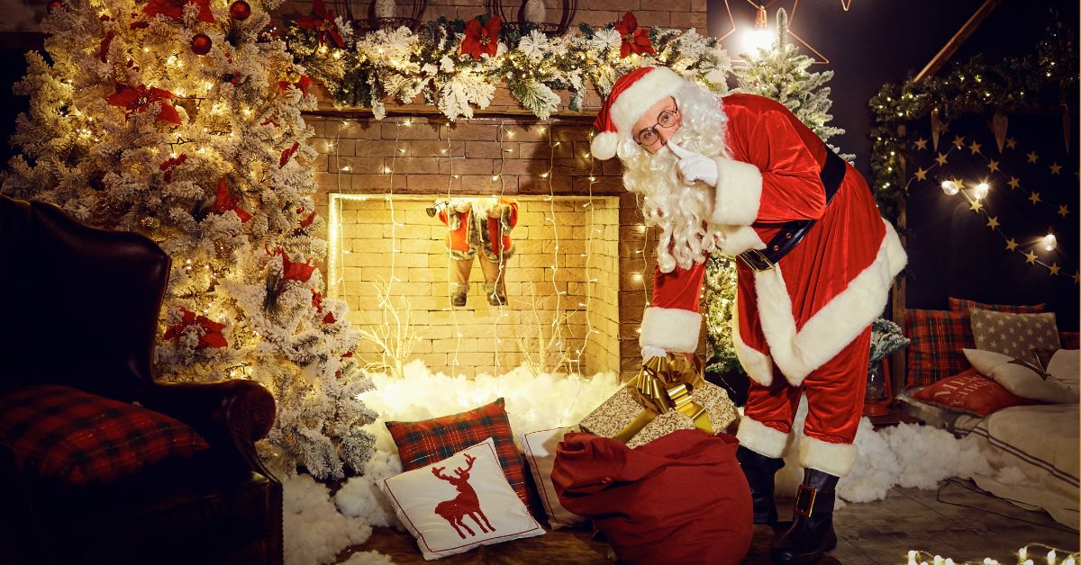 Deda mraz sa poklonima ispred kamina