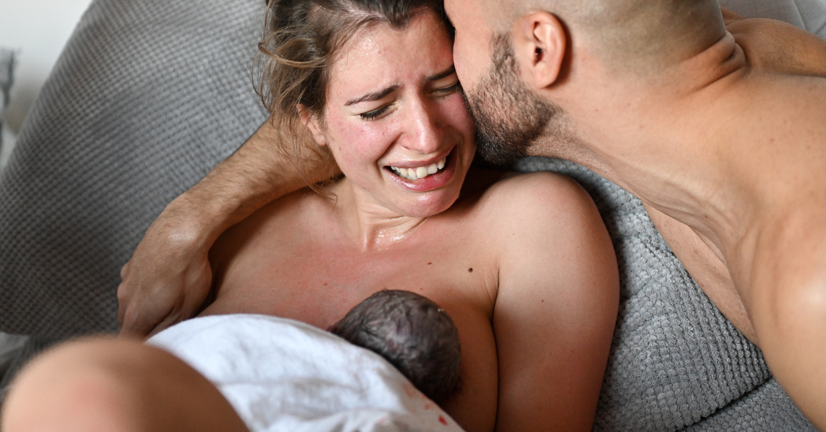 muž ljubi ženu na porođaju a ona drži bebu na grudima