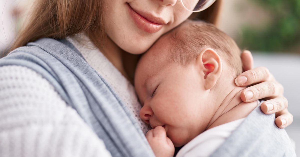 Mama drži bebu koja spava na grudima