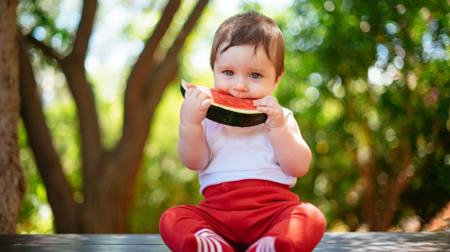 Beba sedi i jede krisku lubenice