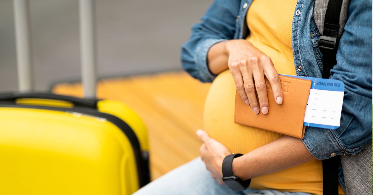trudnica sa koferom drži pasoš na aerodromu