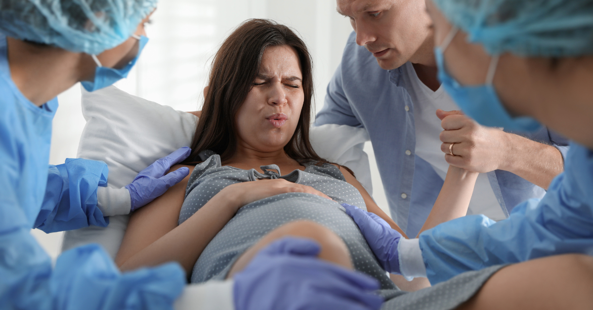 žena se porađa u sali, lekari, muž je drži za ruku