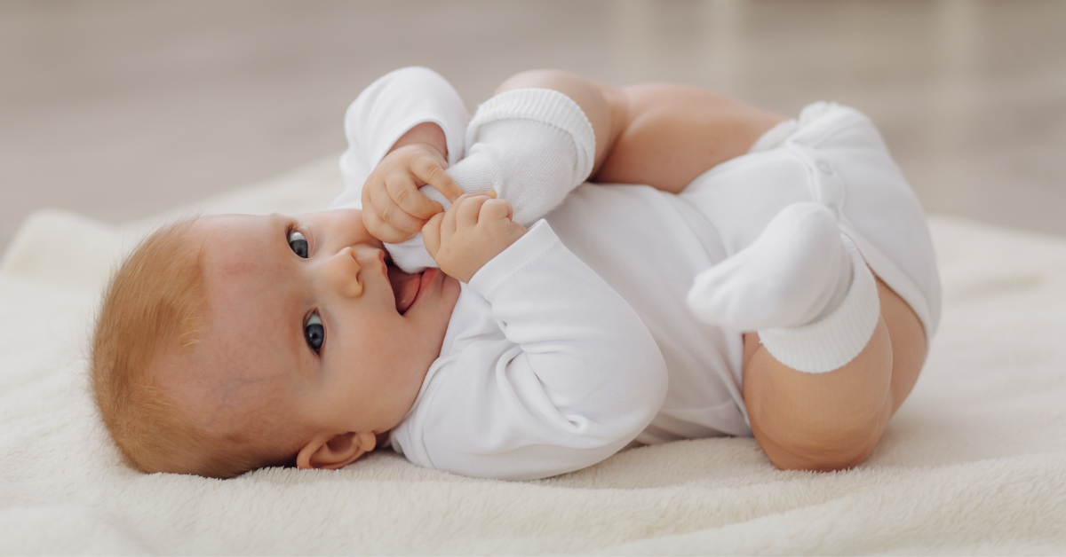 Beba leži i stavlja nogicu u usta