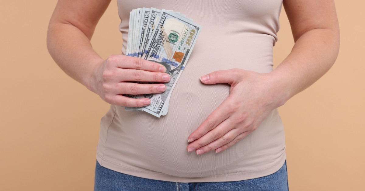 Surogat majk drži dolare u ruci a drugu ruku na stomaku 
