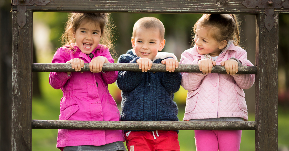Mala deca stoje na drvenoj ogradi
