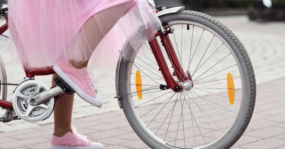 Devojčica u roze suknji i roze patikama na biciklu