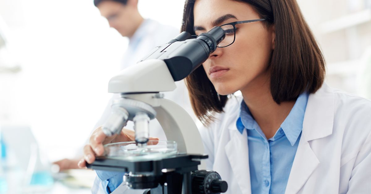 žena gleda kroz mikroskop u laboratoriji
