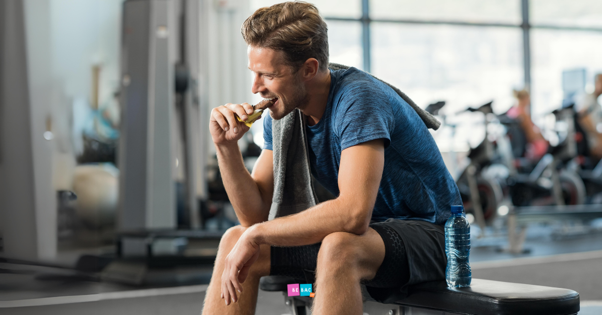 muškarac u teretani jede čokoladicu