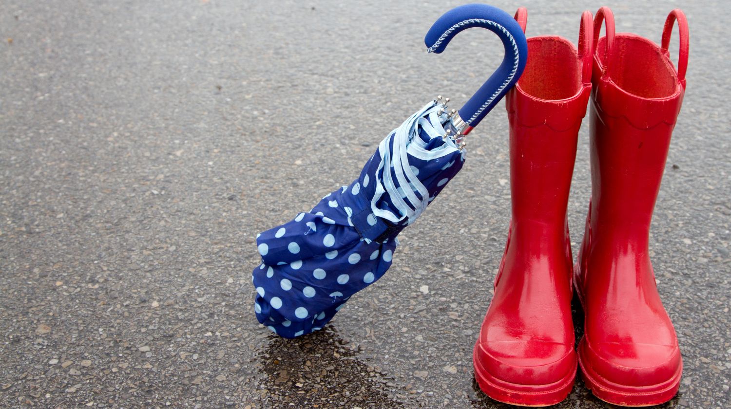 Crvene gumene čizmice i plavi kišobran na tufne