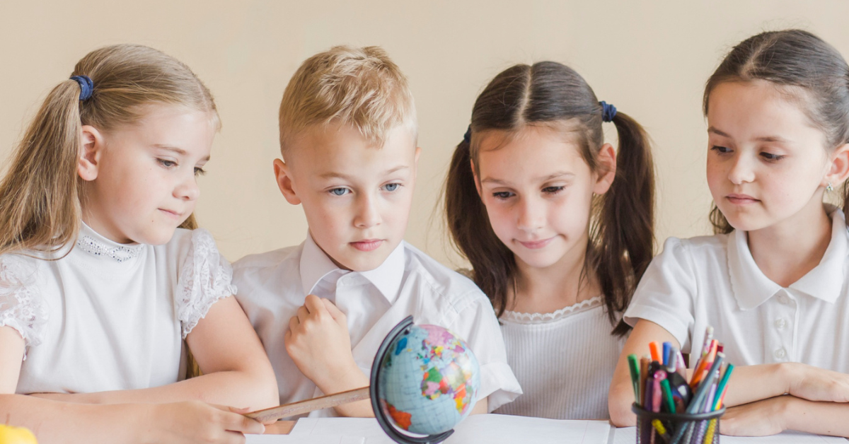 tri devojčice i dečak gledaju u globus u učionici