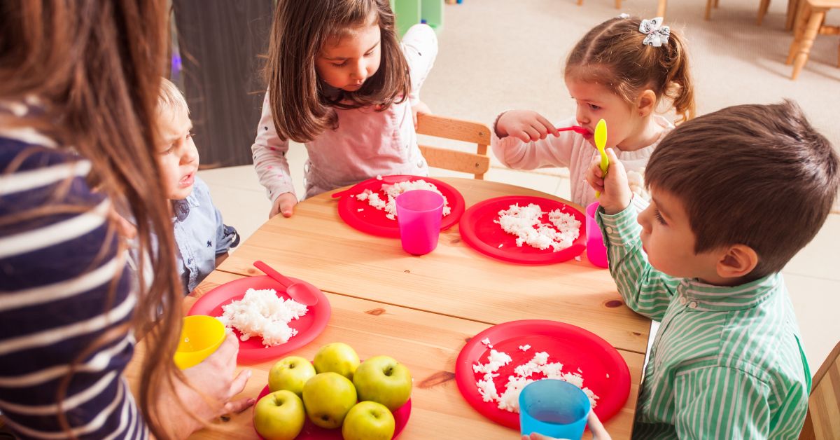 Grupa dece jede hleb i jabuke u vrtiću