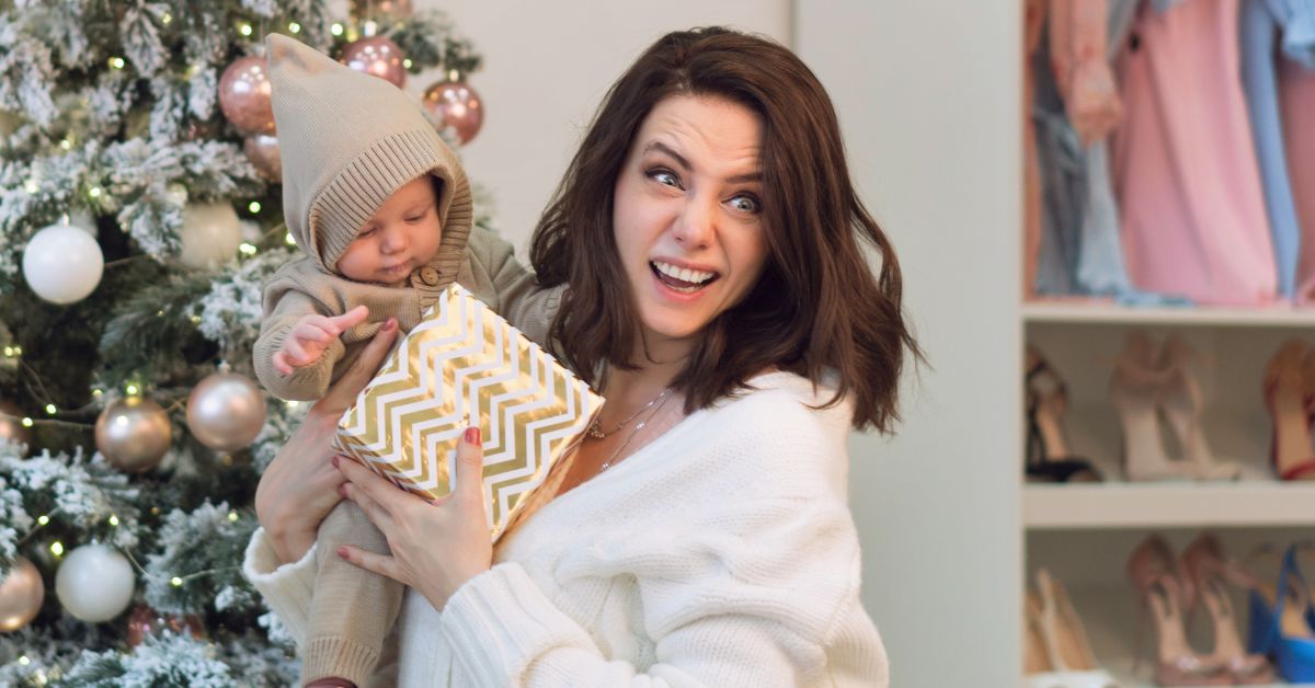 mama i beba drže poklon ispod jelke