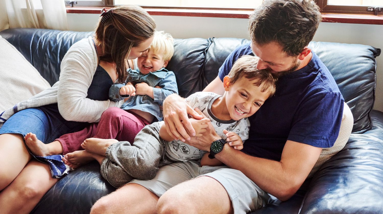 Mama tata i mala deca se grle na kauču