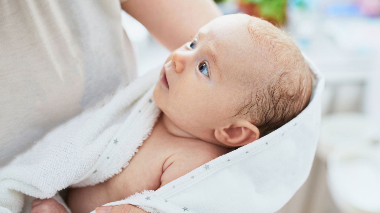 Mama drži bebu umotanu u peškir