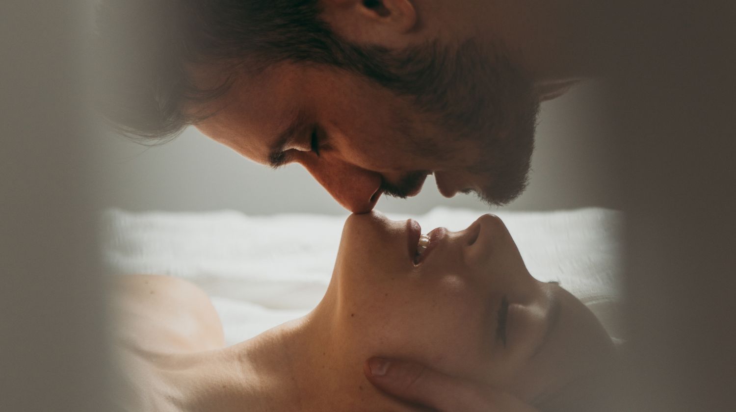 Muškarac i žena na krevetu ljube se