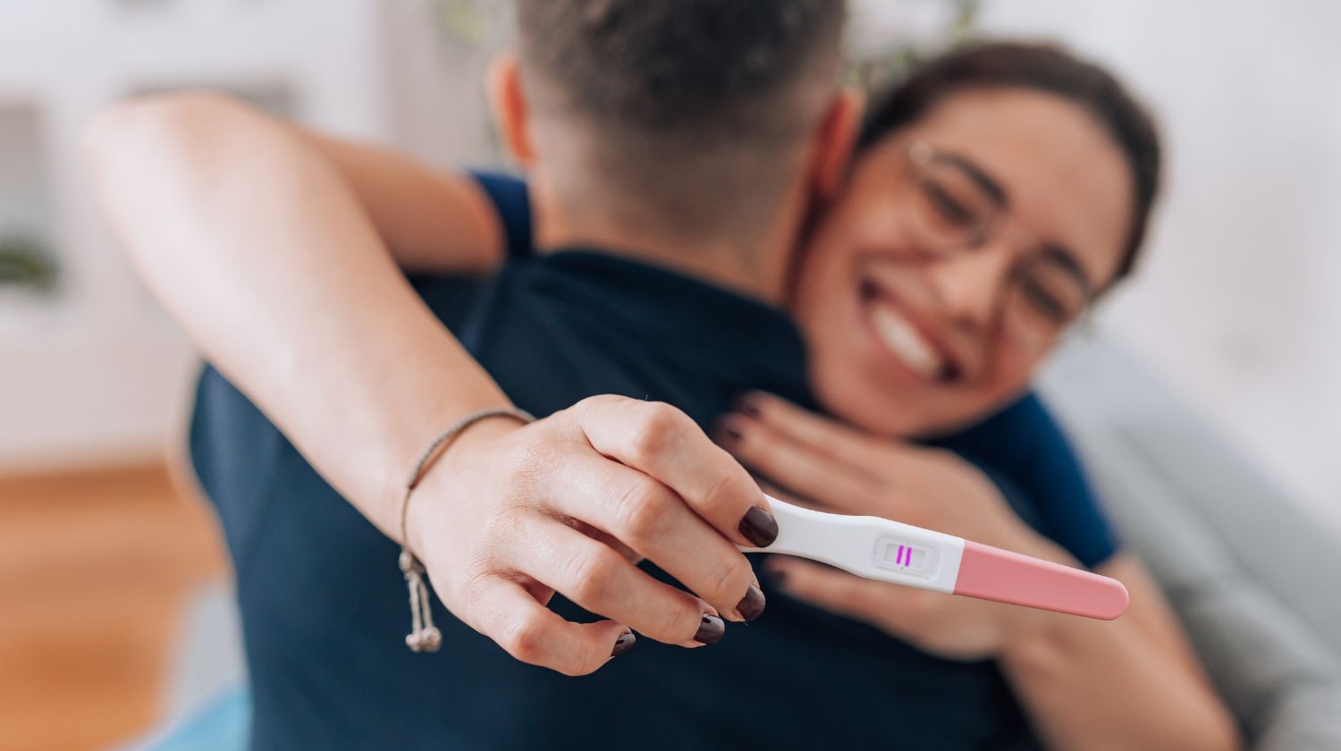 Žena u zagrljaju partnera pozitivan test na trudnoću dve crtice