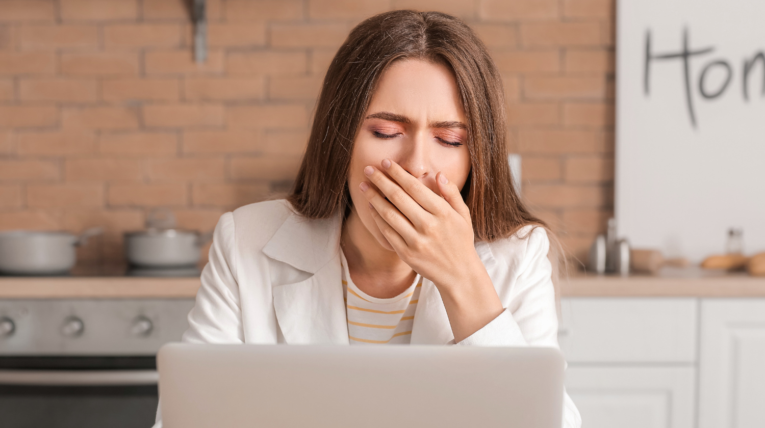 Žena sedi za kompjuterom i zeva