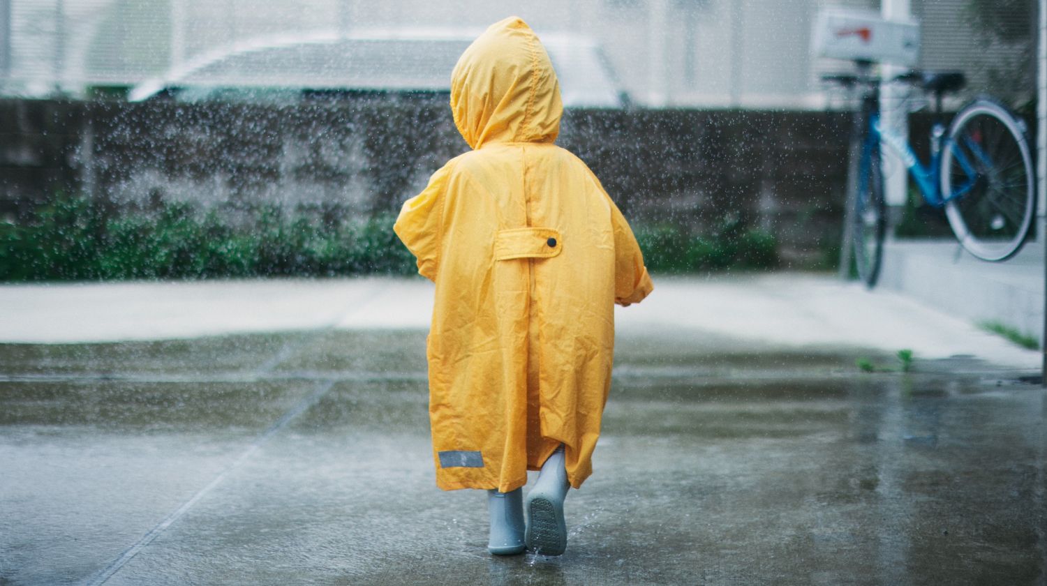 Malo dete u žutoj kabanici na kiši
