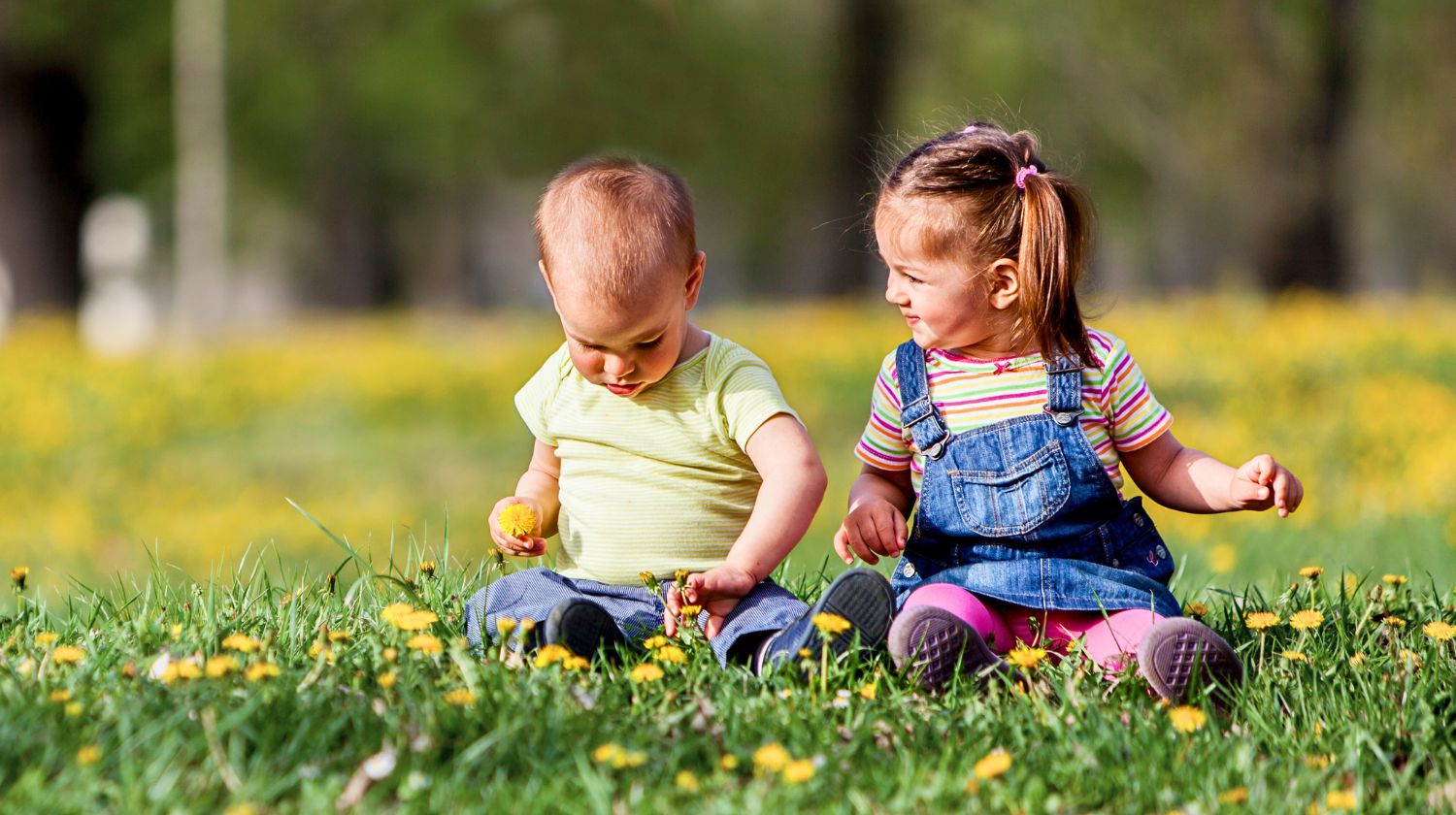 Devojčica i dečak sede na travi proleće