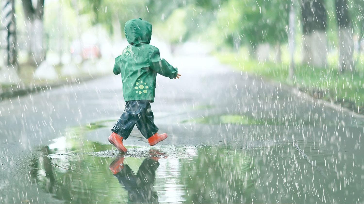 Dete u kabanici na ulici dok pada kiša