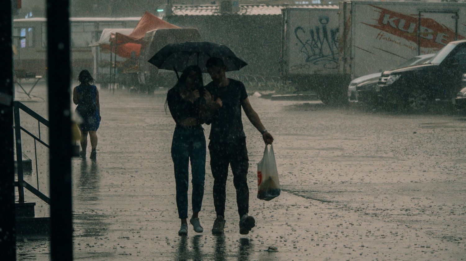 Momak i devojka ispod kišobrana jaka kiša