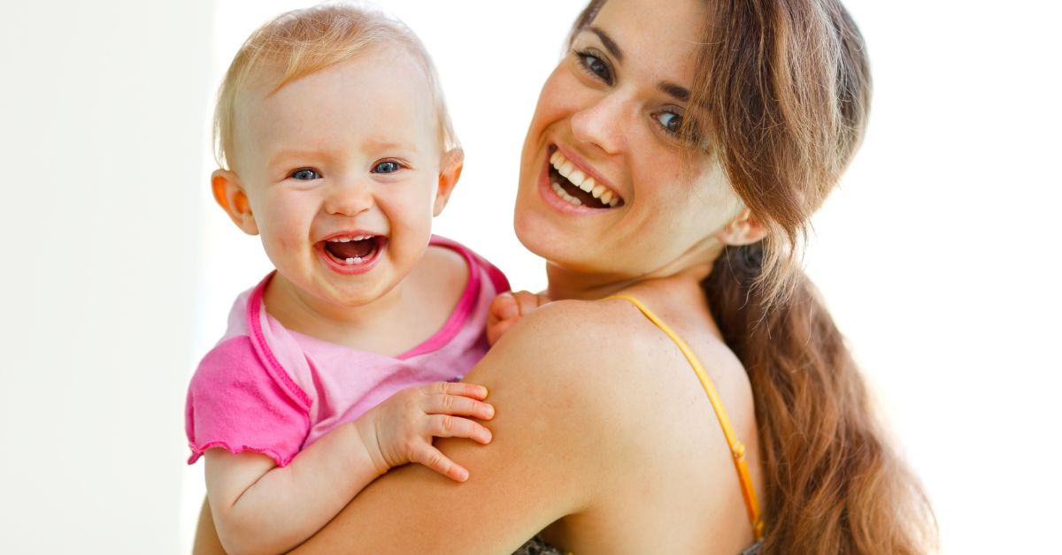 Mama drži bebu u naručju smeju se obe