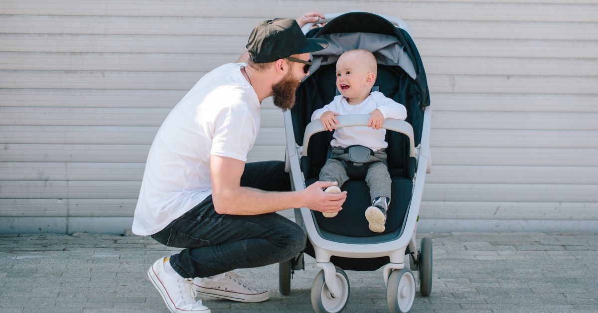 Tata čuči pored bebe u kolicima