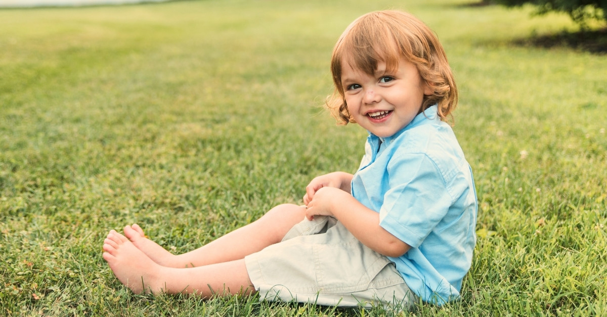 dečak sedi na travi
