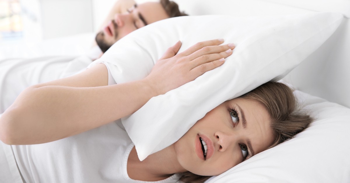 žena drži jastuk preko glave jer muž hrče