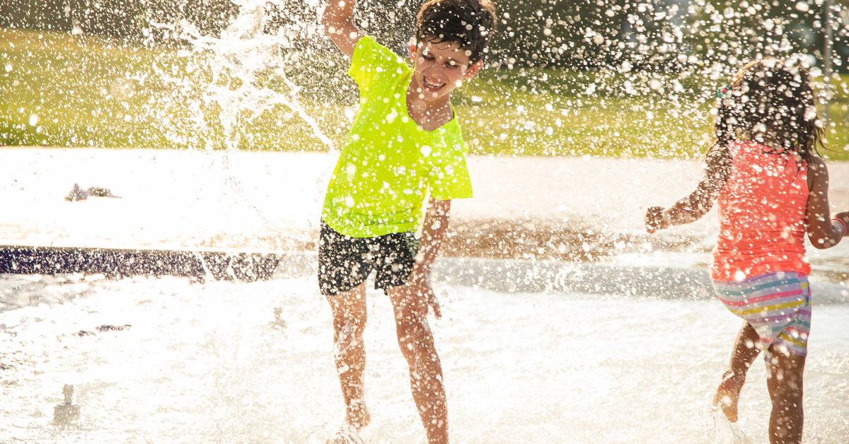 Dečak i devojčica trče kroz vodu iz prskalice
