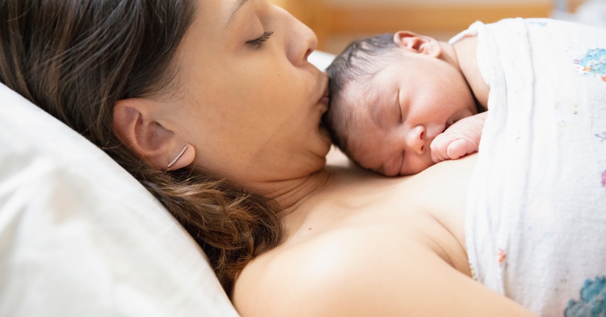 mama ljubi novorođenu bebu