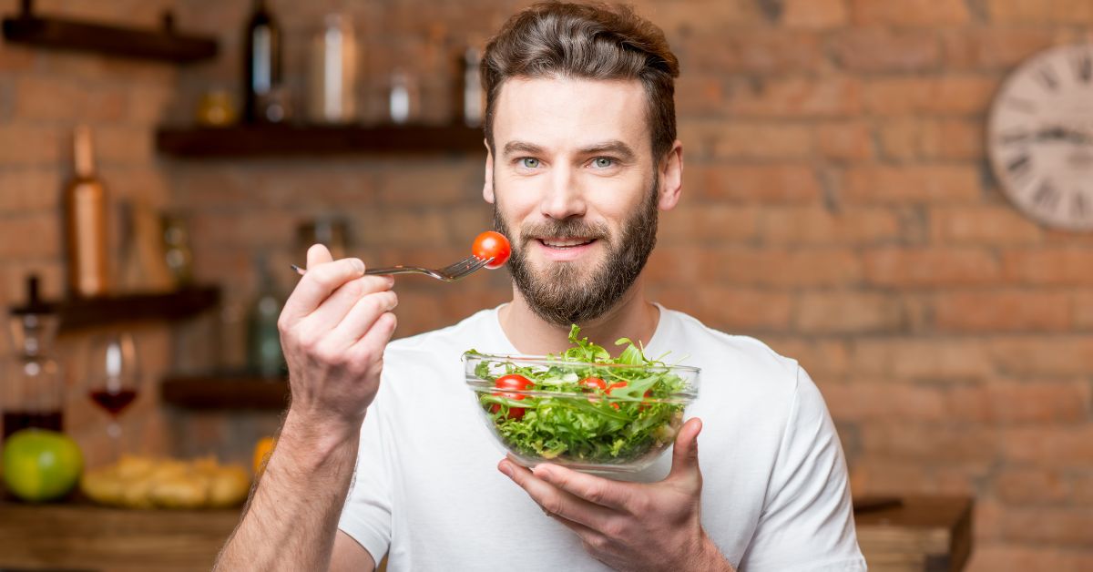 Muškarac jede paradajz i salatu